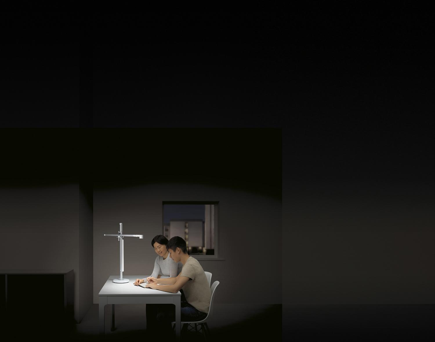 Teenager studies with his mother in powerful desk light